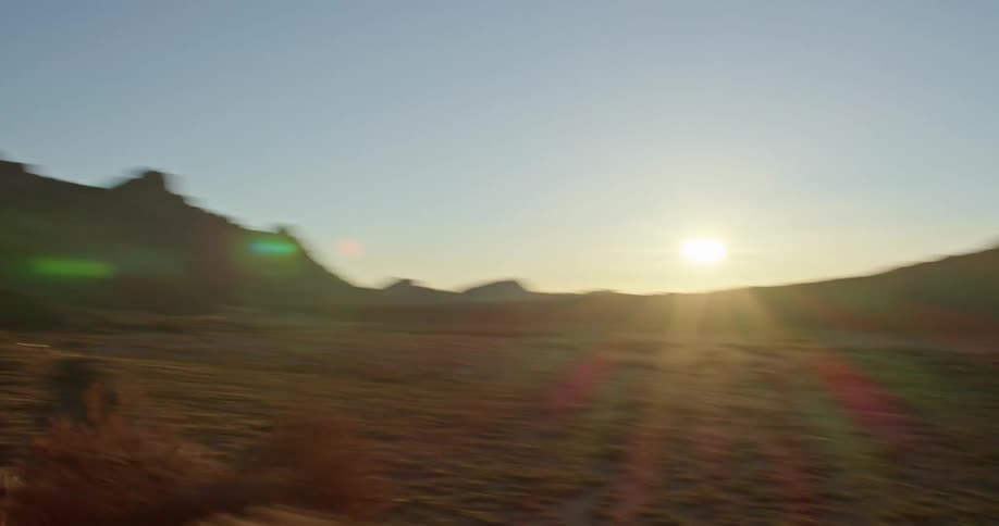 A road in the desert with a mountain range the sky and clouds in the background