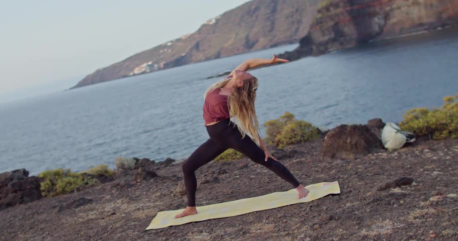 A woman doing yoga out on a cliff