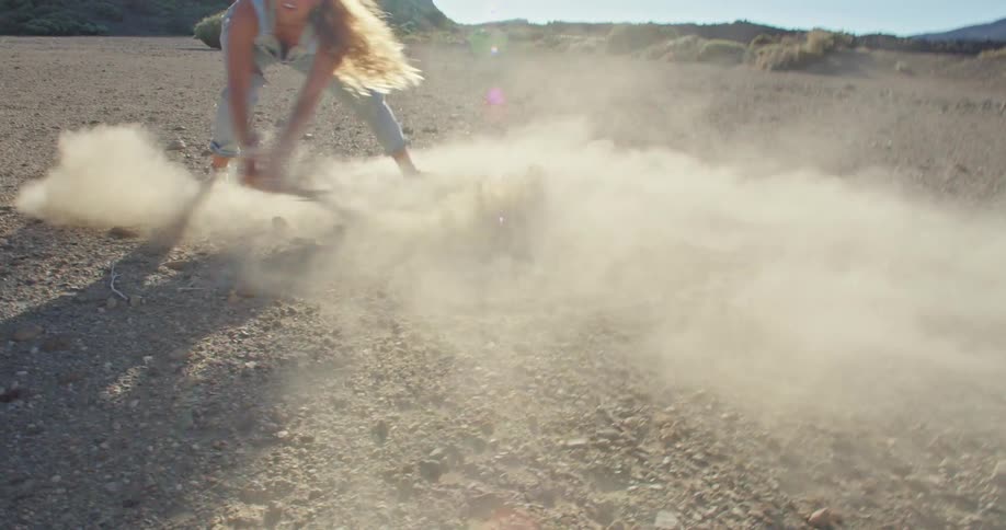 A woman drawing in the sand with a stick outdoors