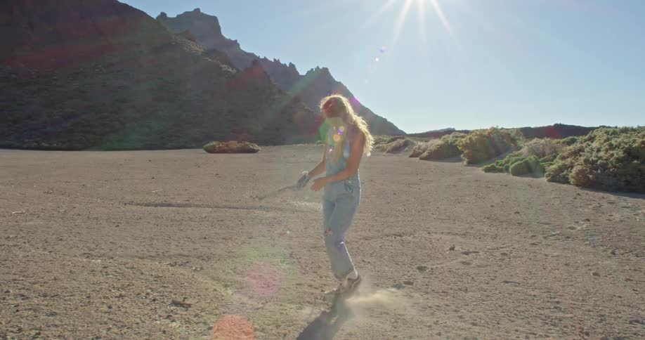 A young woman waves a branch around as she walks through a canyon