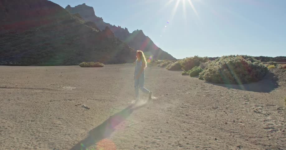 A woman is walking along a valley and stoops to pick up something