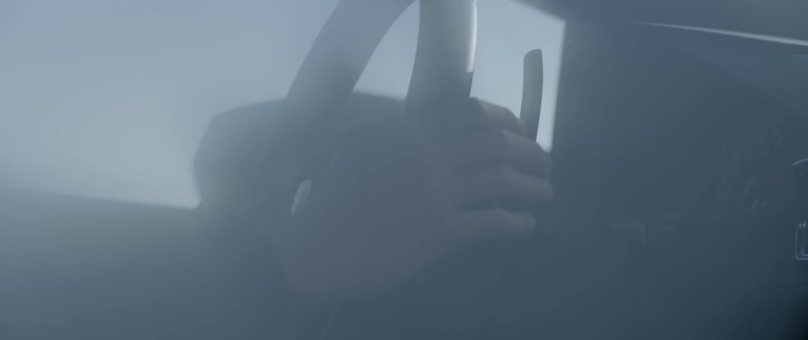 Two hands hold steering wheel while driving