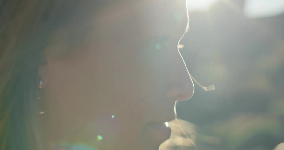 Close up of woman with brown hair and earrings looking around as the sun shining