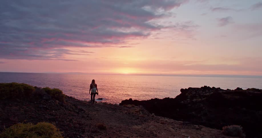 A woman hiking on a cliff at sunset