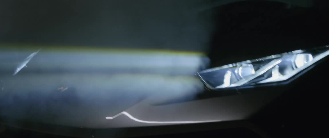 A car's headlights are shown driving in the dark