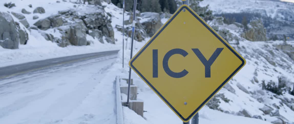 A sign says icy on this snow covered road