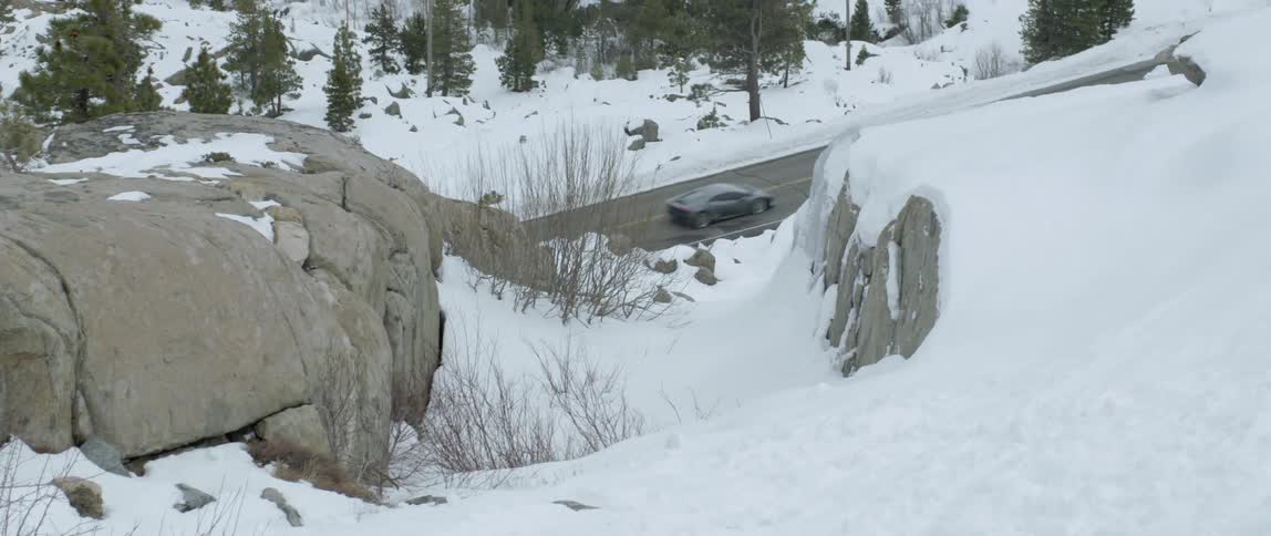 A view of a small road as seen from the top of a snow covered hill