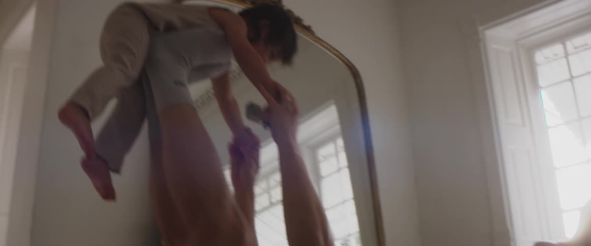 A man in a room playing with a child with a mirror a wall and window in the background