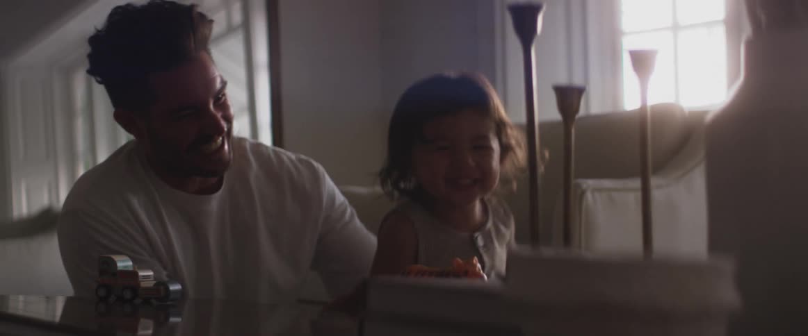 A father and child laugh as the child squirms away from the man