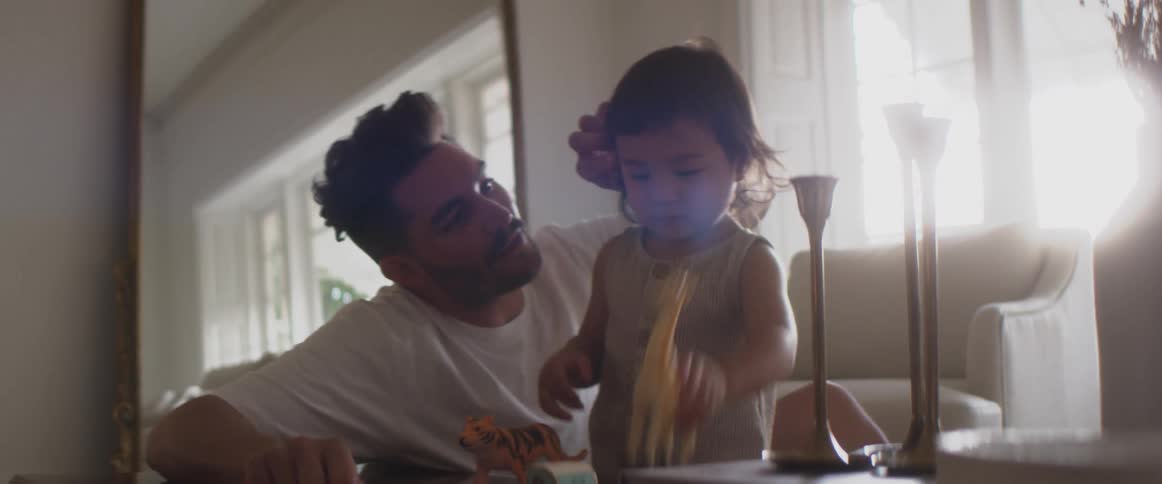 A father kisses the arm of a child as they play with toys