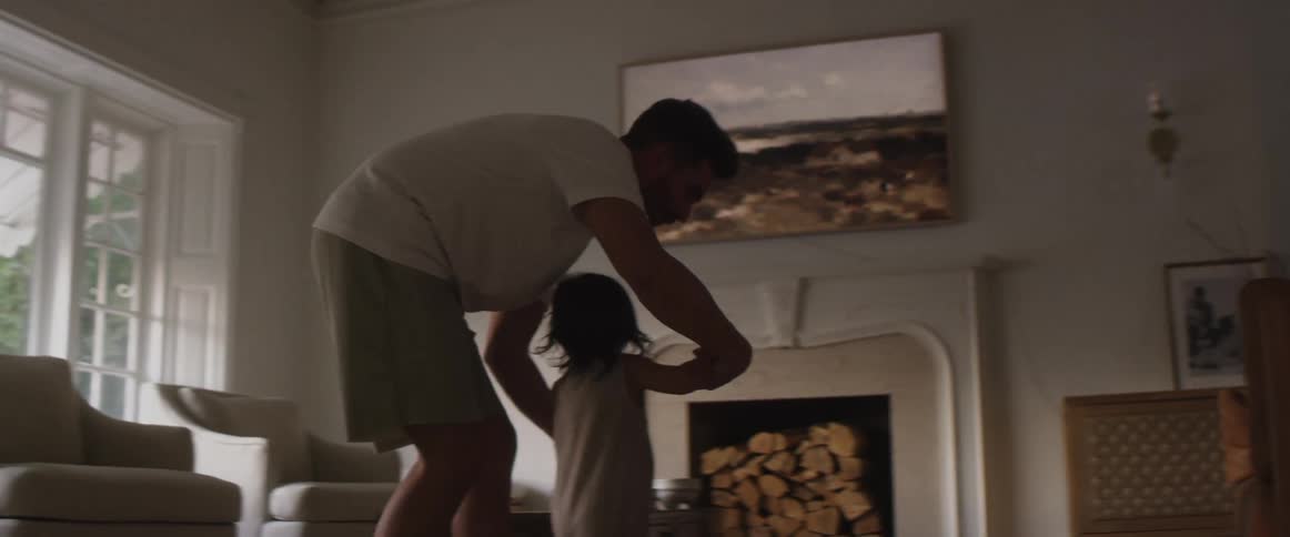 Father holds his child while they run in the living room