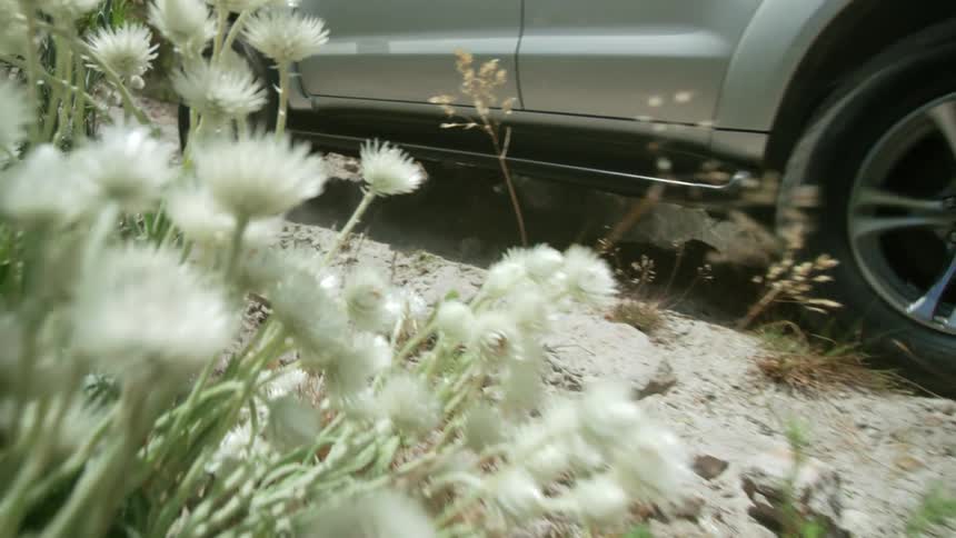 A vehicle travels up a gravel road on a hillside during the day