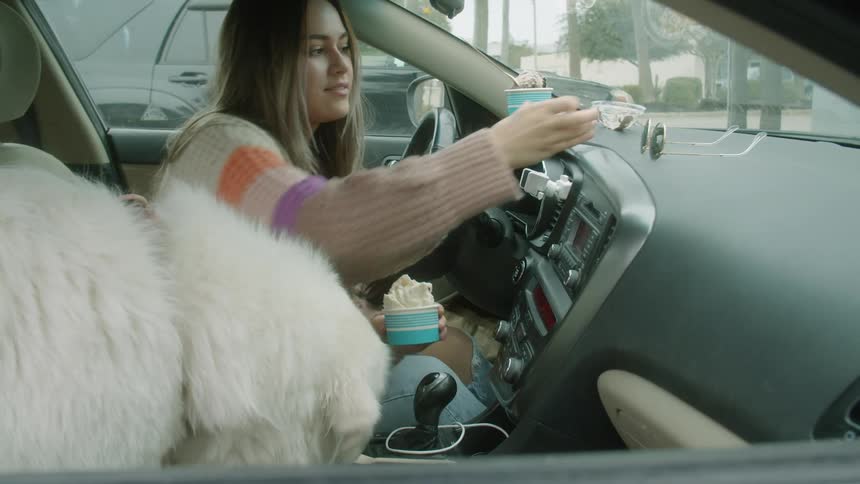 A woman is feeding some ice cream to her dog