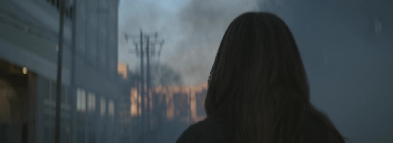 A woman is walking through a smoky city street in the early morning