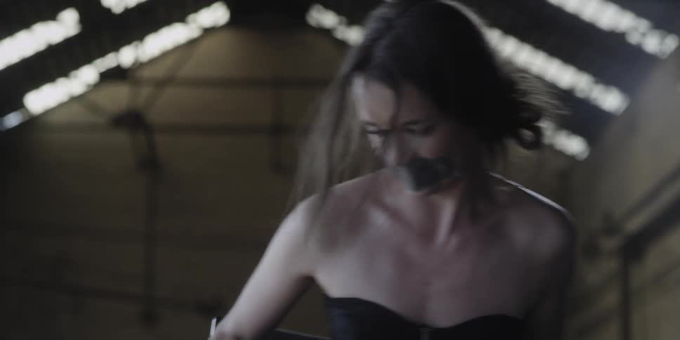 A woman with duct tape on her mouth is struggling and falls over