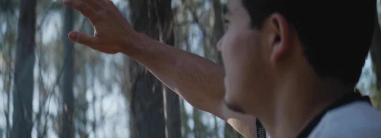 A man has his arm raised while standing in a forest