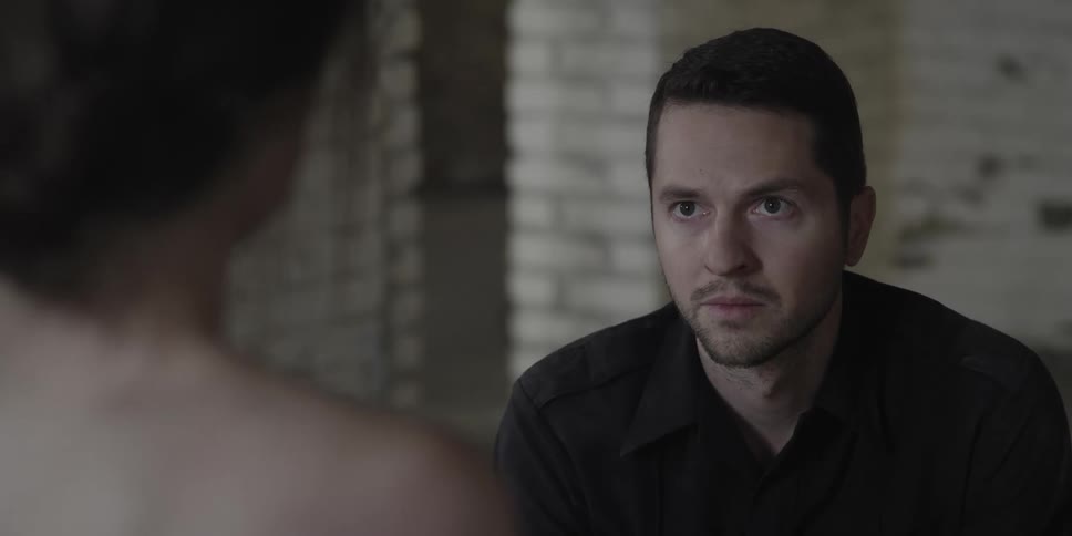 A man and a woman in a room sitting with another man tackling the man with a wall in the background