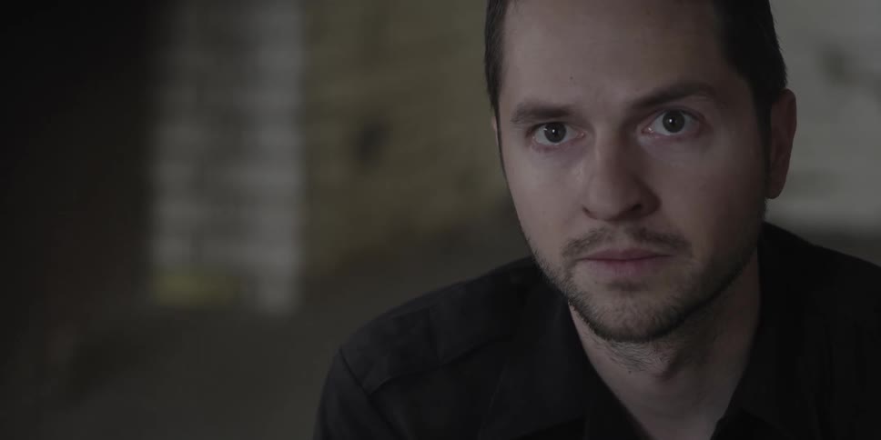 A man in a room with a wall in the background