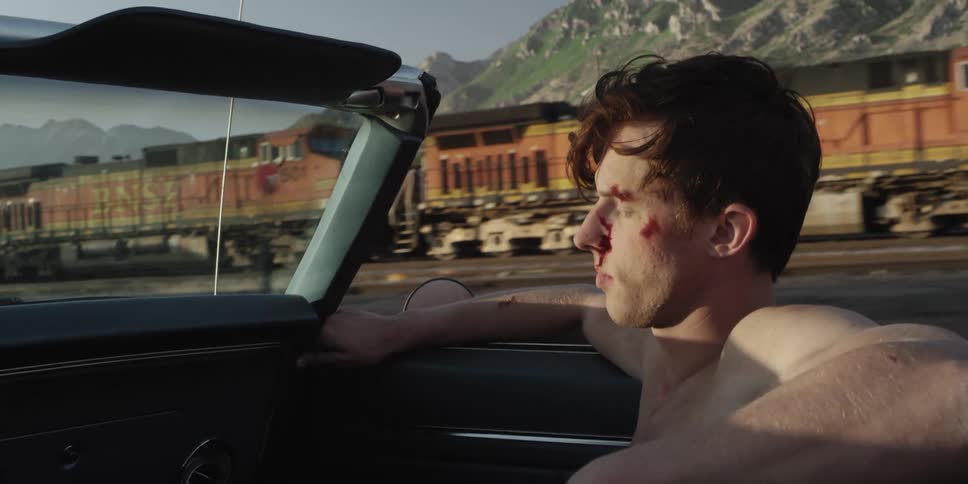 A man riding in a convertible down a road