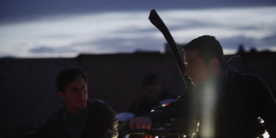 A man talks to his friend on another motorcycle
