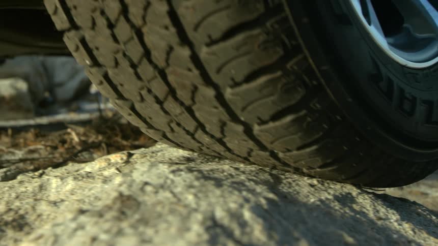 A vehicle tire driving on rocks