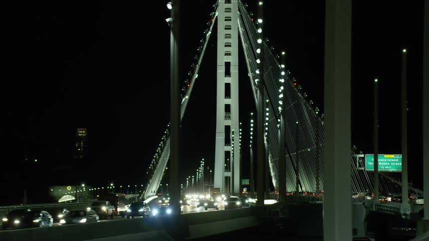 Cars driving across a city bridge at night
