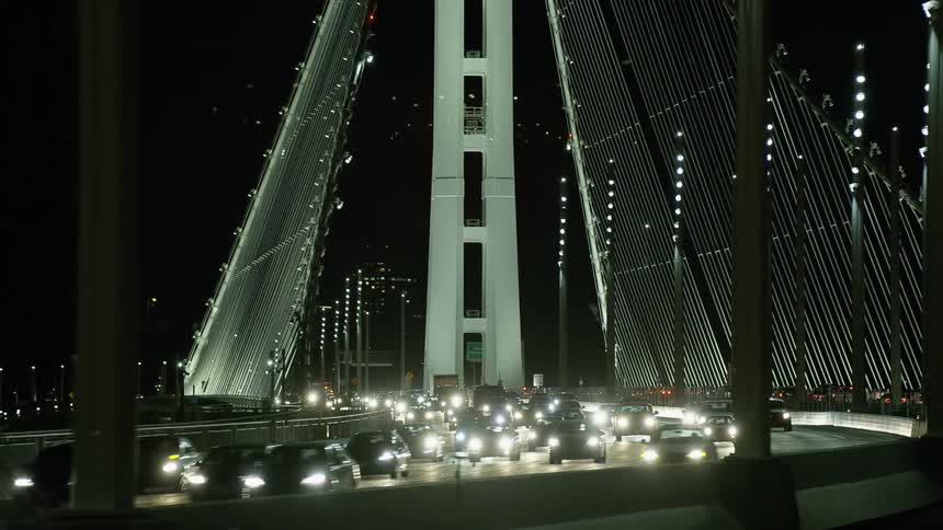 An impressive suspension bridge is illuminated at night as vehicle traffic streams across it