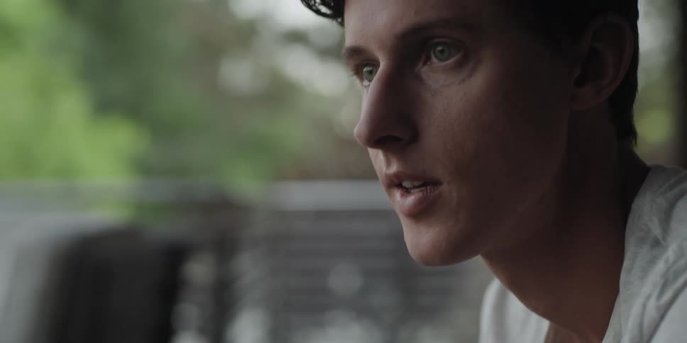 A teenage boy outside talks and lifts his head up