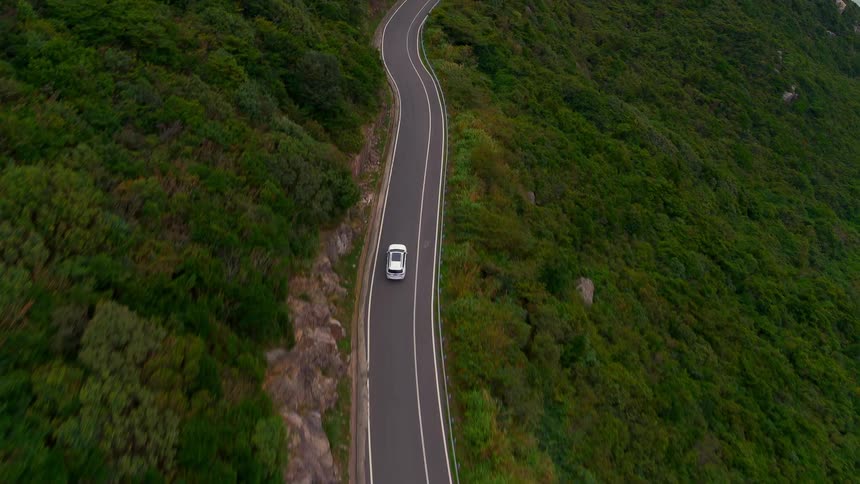 A car traveling on a highway surrounded by trees and near the coast