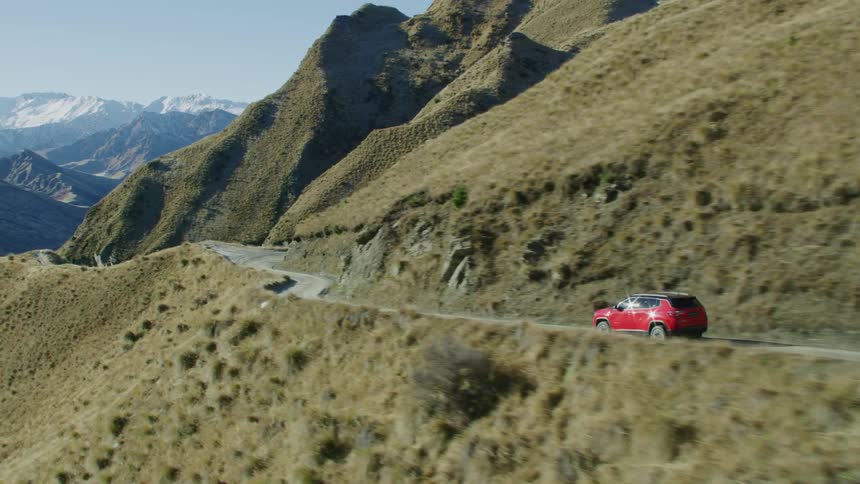 Aerial view of red car driving on high mountain road