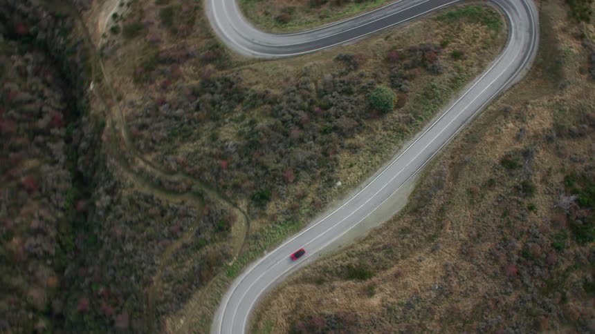 Aerial view of a red car traveling on a winding road