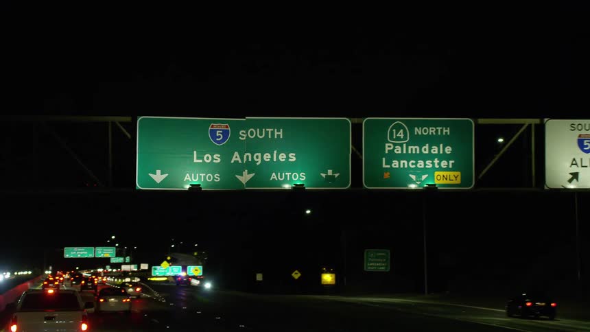 A highway with vehicles signs and streetlights
