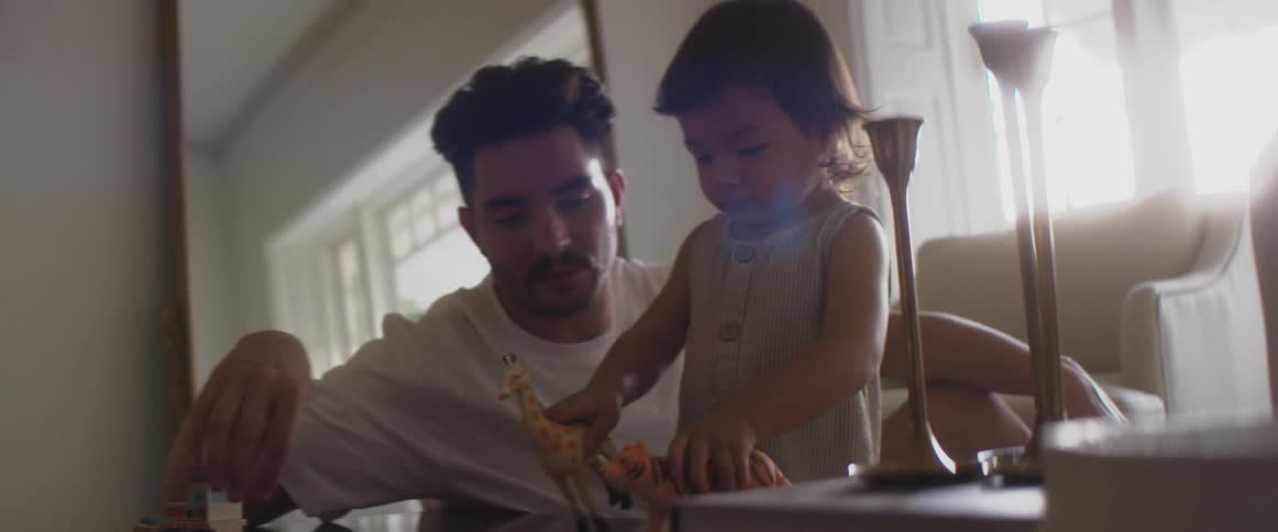 Father playing with toys with his child in the living room at home