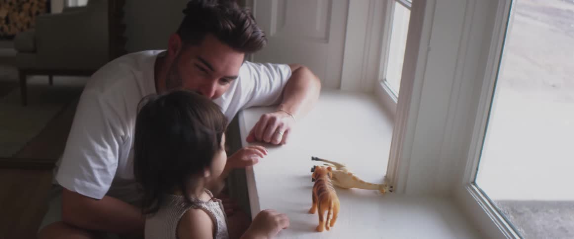 Father playing with child near a window at home