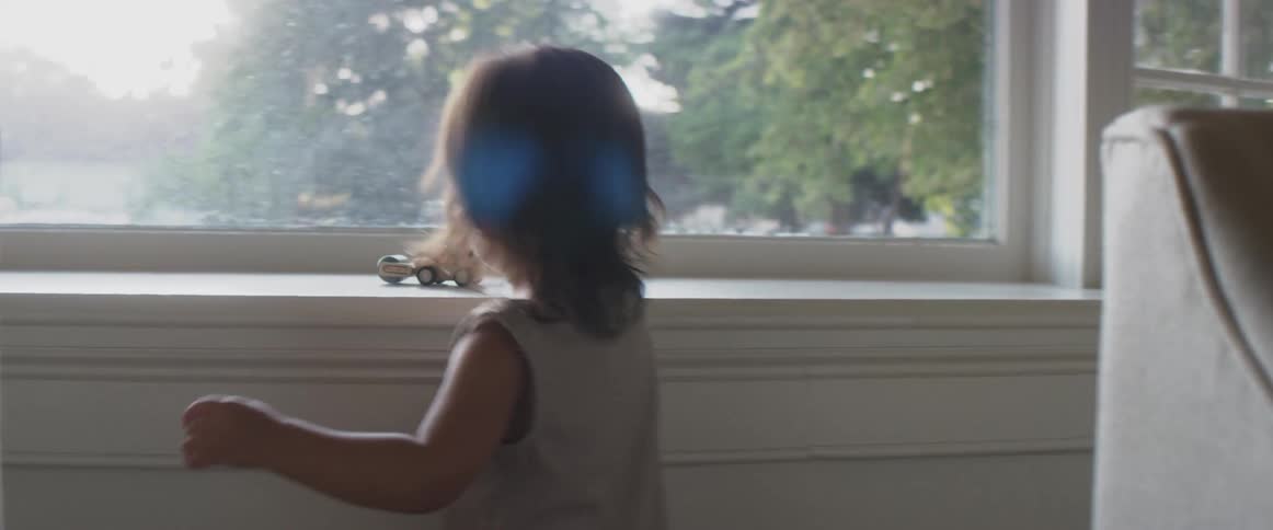 Child plays with toy car on window sill in living room