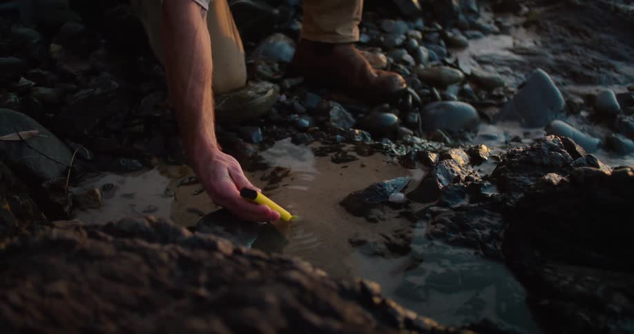A man puts an instrument into some water as a woman watches nearby