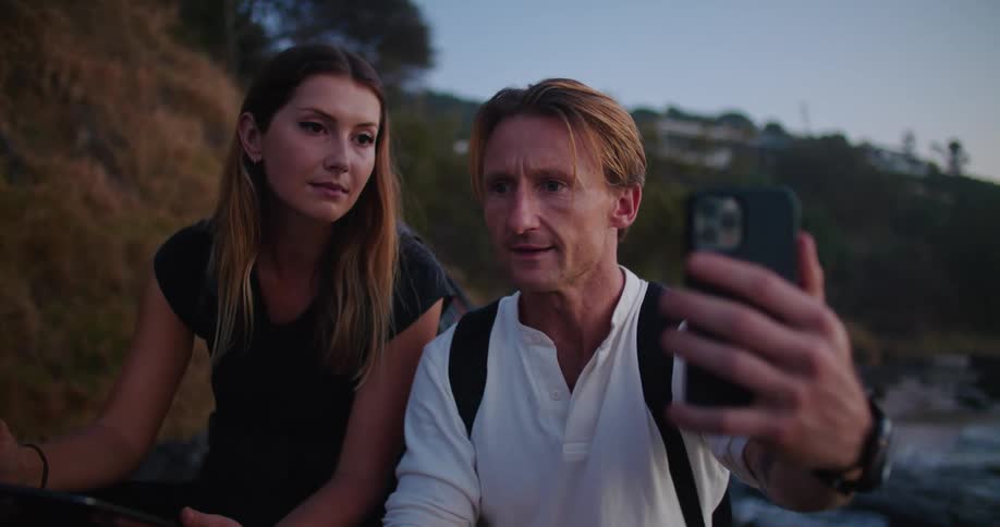 Young couple talking on a video call on a smartphone at the beach