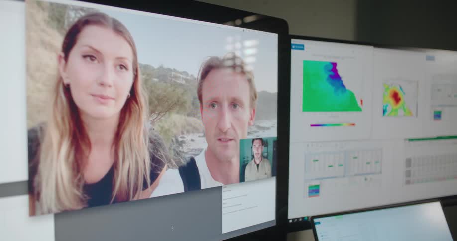 A person using a computer at a desk participates in a video chat with a couple on the coast