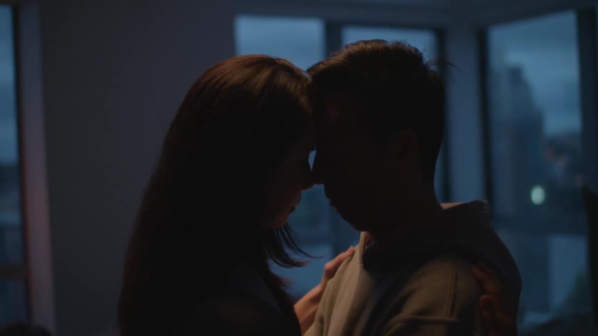Young couple slowly dancing on a dimly lit room in an apartment at evening
