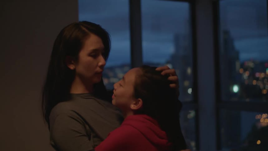 Mother and daughter hugging on the living room of an apartment in the city
