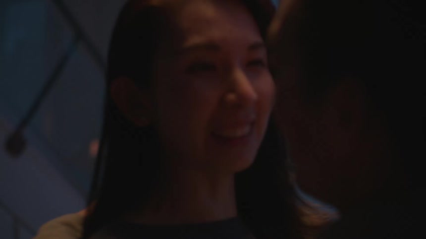 Young couple hugging and talking while dancing on a dimly lit room at home