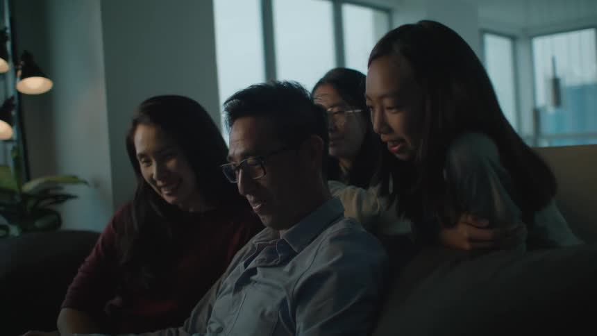 Happy family of four sitting together on a couch at home