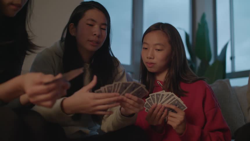 A family sits at home and laughs as they play cards together