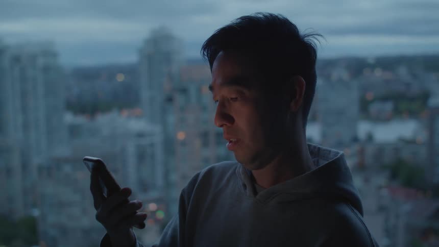 Man standing near the apartment window talking on the phone