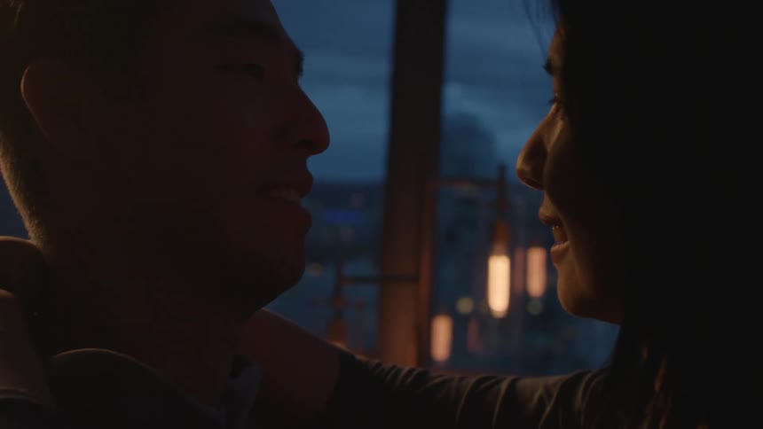 A couple kiss as they slow dance in their downtown apartment