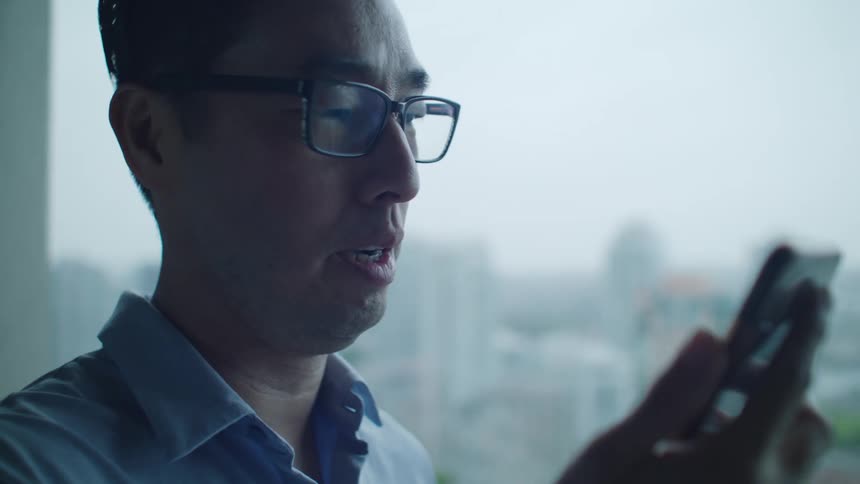 A man with glasses using a smart phone