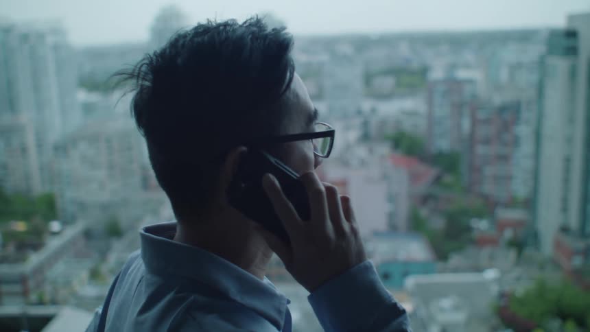 Man talks on the phone while standing on the apartment balcony
