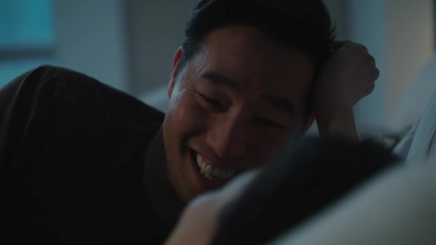 A couple laugh while lying in bed together