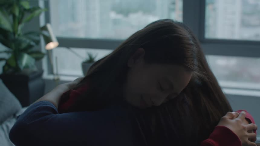 One woman hugs and comforts anotherwhere they sit on the bed