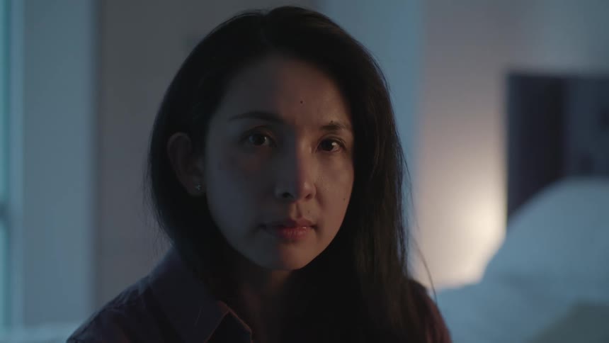 A female asian standing in a bedroom smiling and laughing